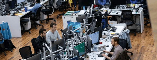 A quant trader watching live markets beside a quant researcher analysing model output